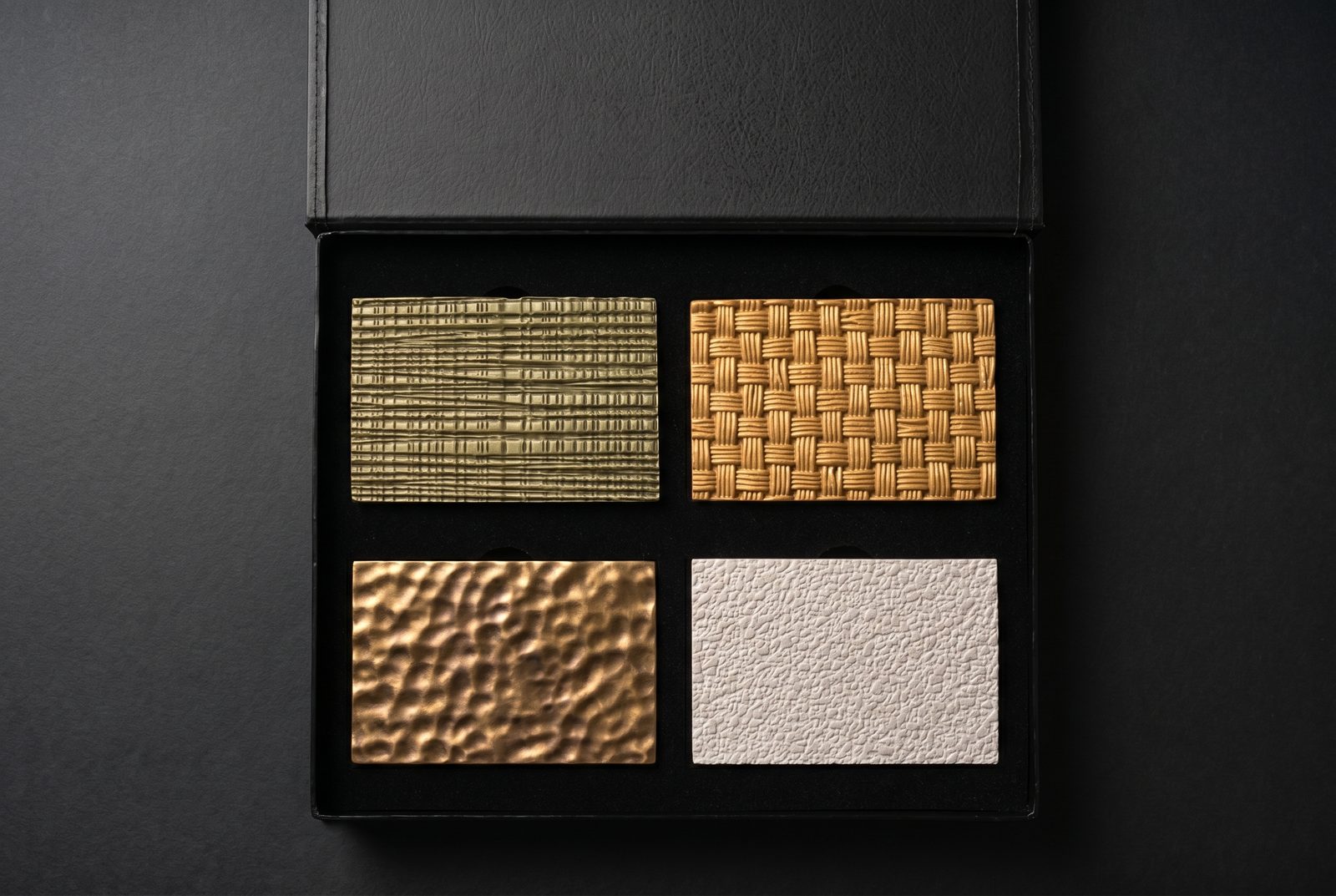 Studio Luminant finish sample box, open — four architectural relief finishes